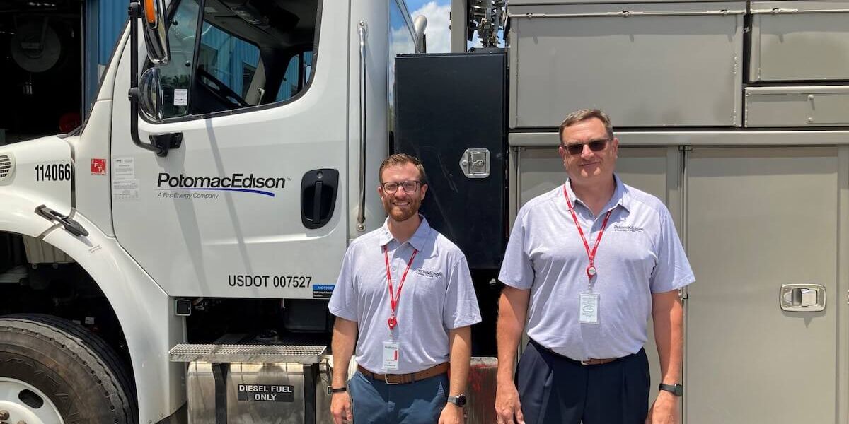 Two individuals participating in the Maryland Chamber Foundation's Teacher Externship Program pose in front of an Potomac Edison utility truck.